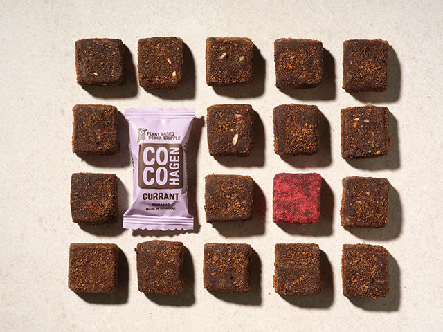Chocolate truffles arranged in a grid with a Cocohagen packaging in the center on a beige background