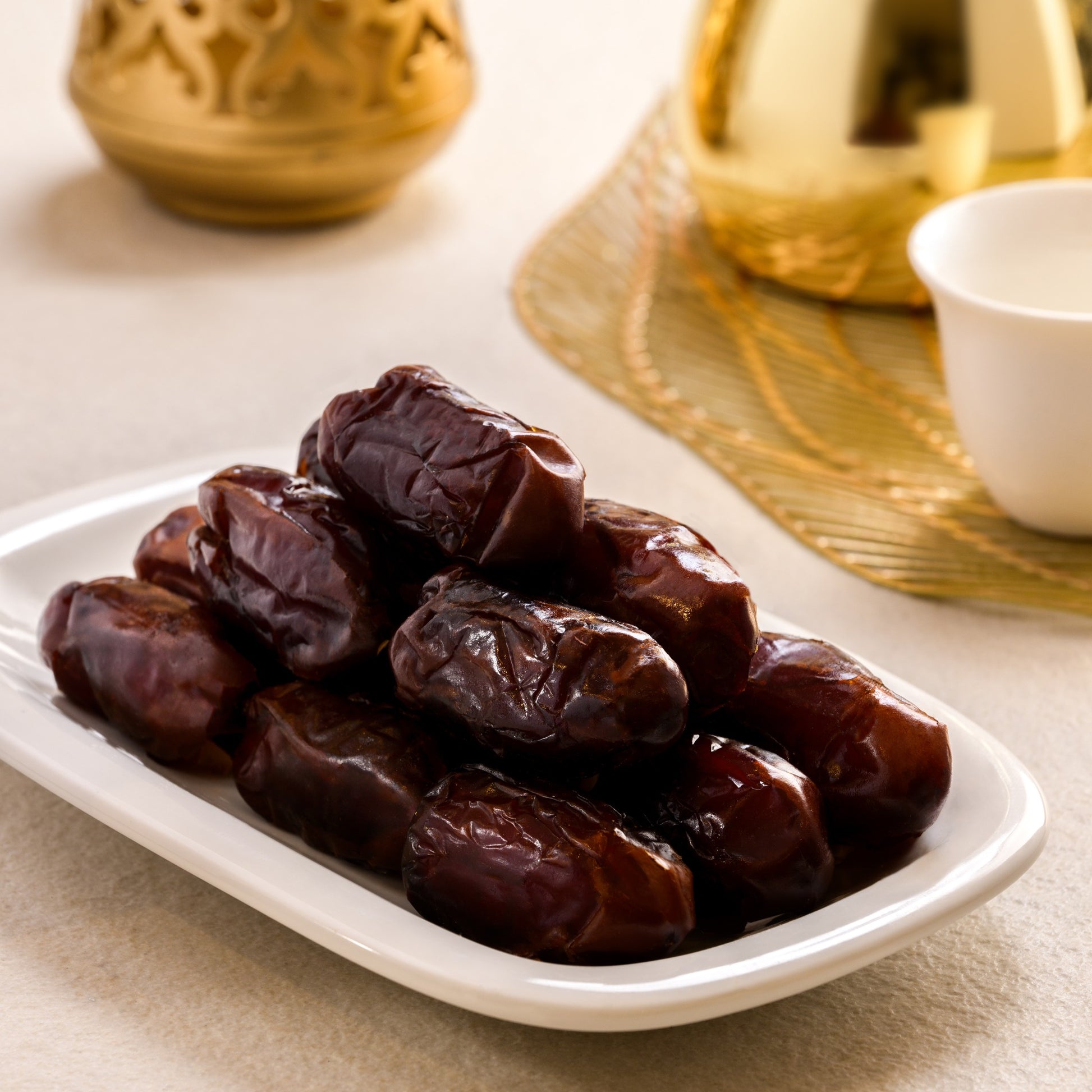 Khidri Date fruits on a white plate with gold decorative elements in the background